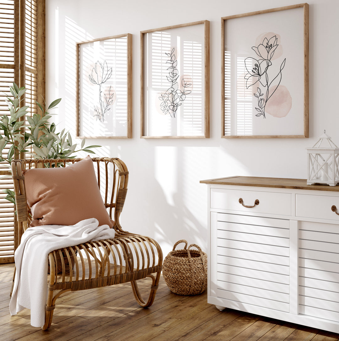 Three unframed botanical art prints styled above a modern bed in a neutral bedroom interior